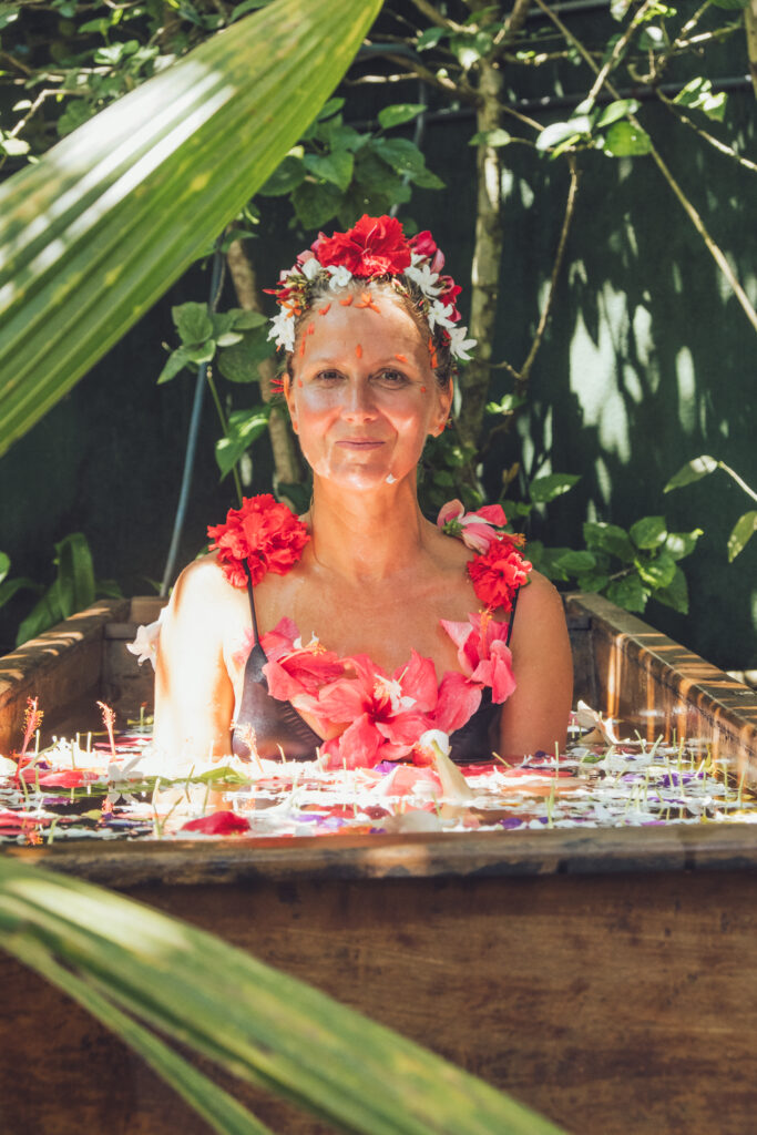Staacy Cannon sitting in an outdoor Ayurvedic flower bath adorned with flowers.